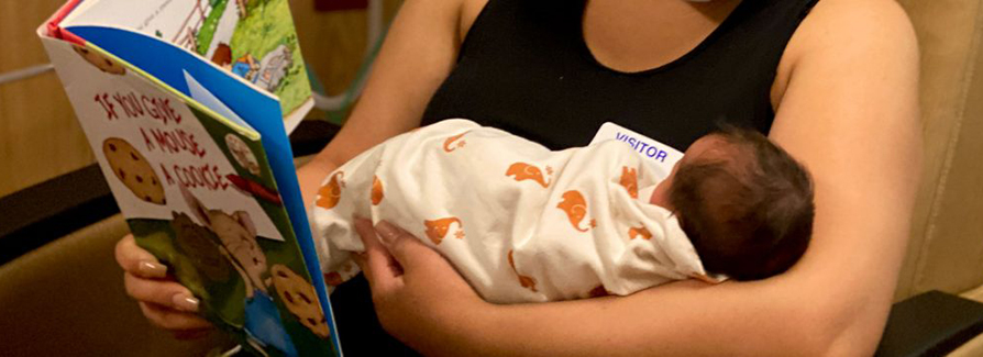 Mom reading book to newborn