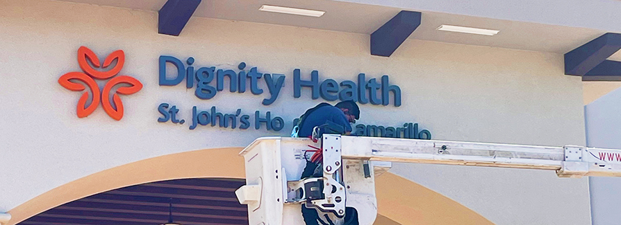 Worker in crane fixing hospital sign